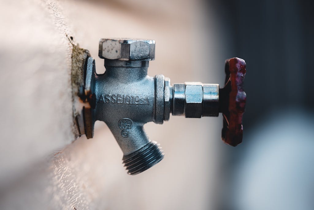 Detailed close-up of a metal faucet mounted on an exterior wall with visible textures.