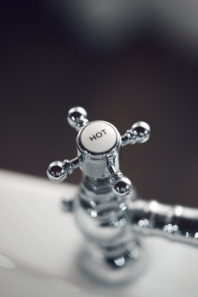 Elegant vintage chrome faucet handle labeled 'Hot' with blurred background.