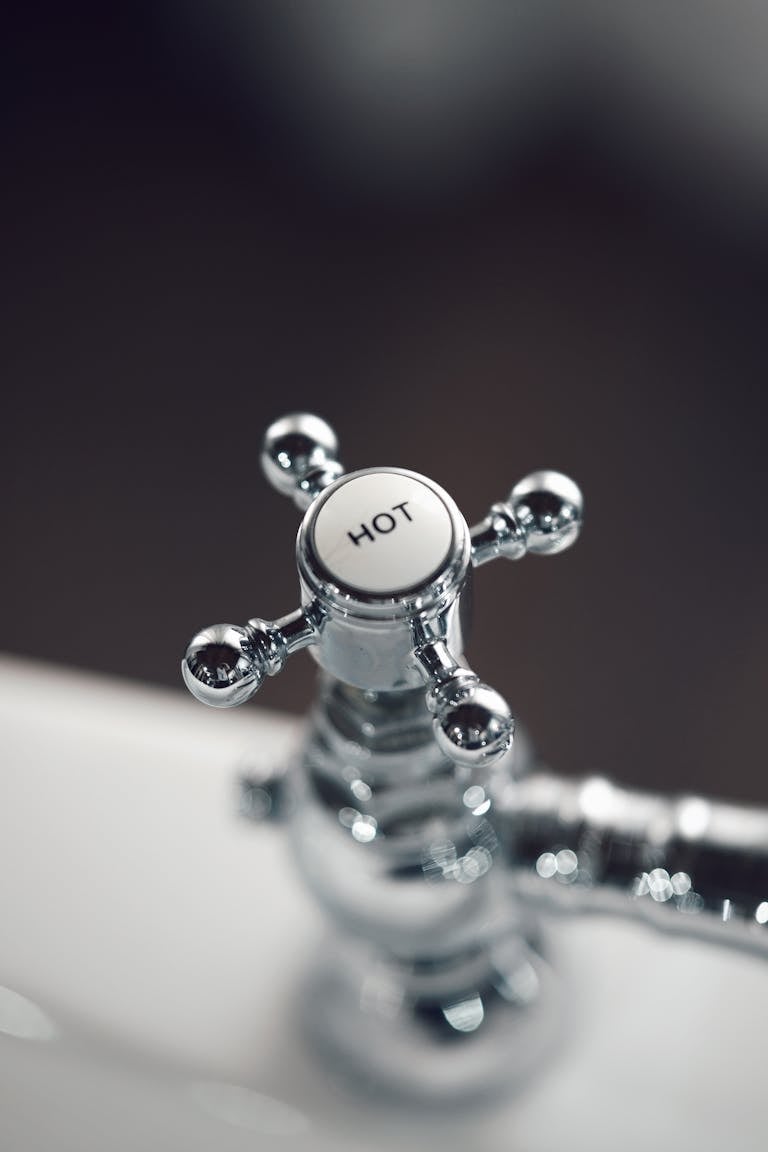 Elegant vintage chrome faucet handle labeled 'Hot' with blurred background.
