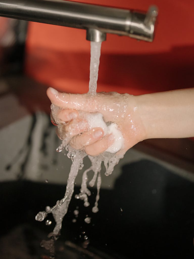 A close-up shot of hands washing under a running water tap, highlighting hygiene.